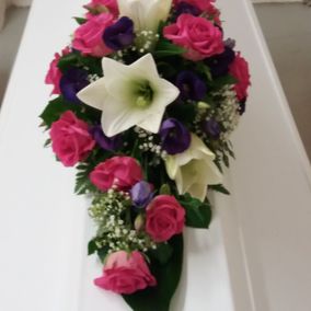 Pinkeistä, violeteista ja valkoisista kukista sidottu hautavihko